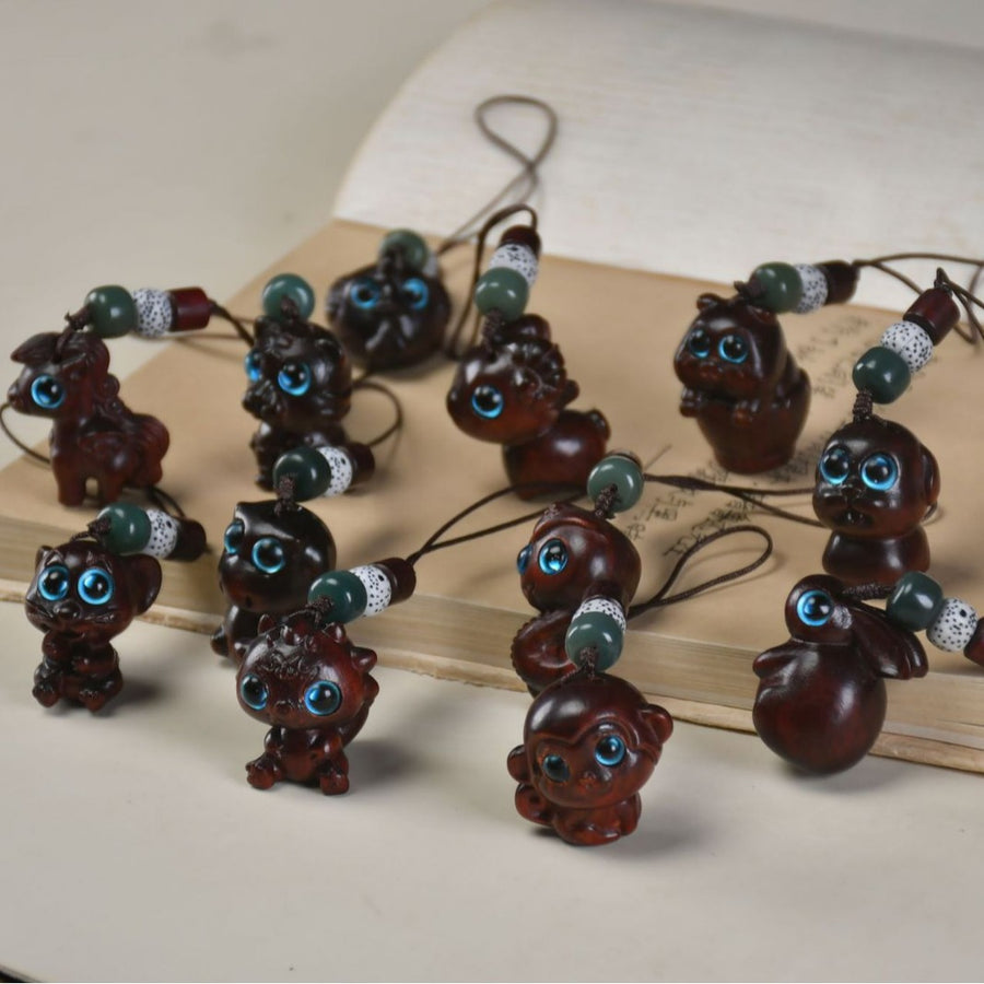A collection of small carved wooden zodiac animal charms with blue eyes and beaded strings.