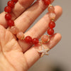 Close up of red agate and sunstone beads with a gold star charm on a wrist