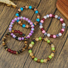 Collection of colorful glass bead bracelets with tiger eye and crystal accents on a wooden surface