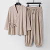 Beige two-piece men's outfit with wrap top and drawstring pants hanging on black hangers