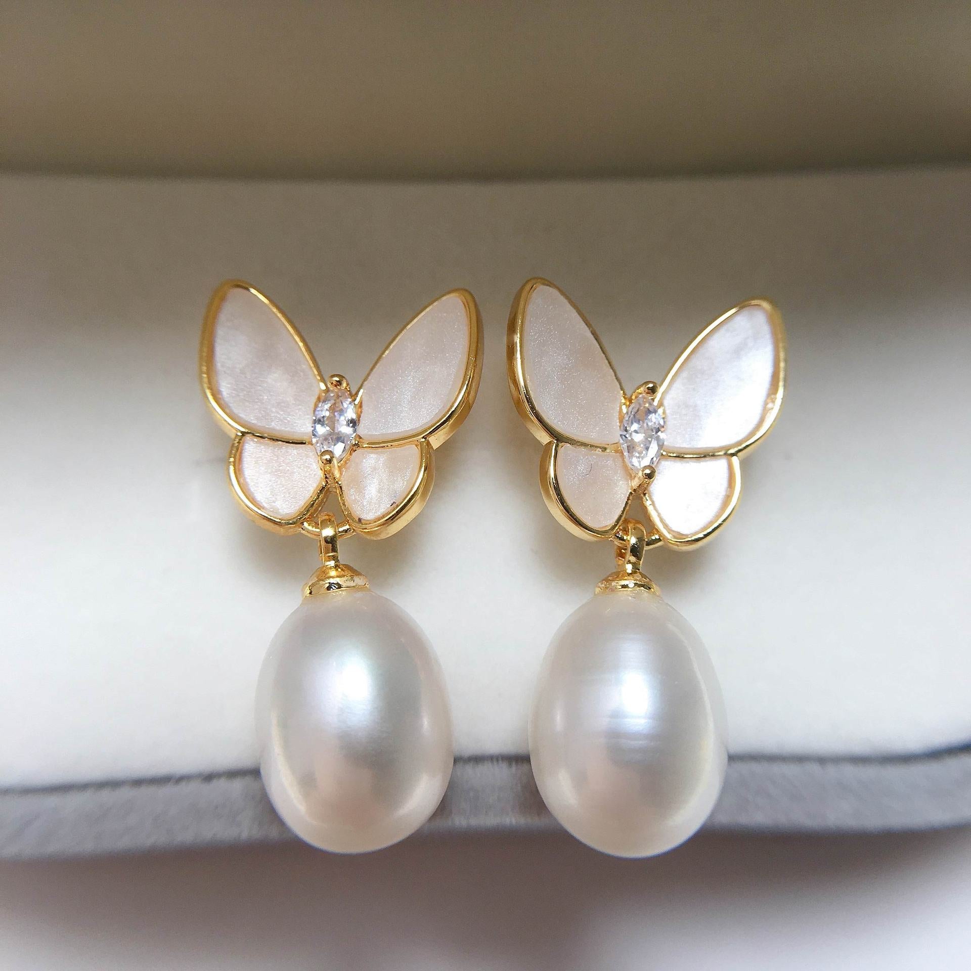 Close up view of gold butterfly earrings with white freshwater pearls