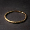 Close up of a handmade copper and brass bead bracelet on a dark surface