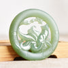Close up of a round light green jade pendant with a carved nine tailed fox design inside