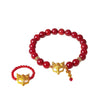 Close up of a red beaded bracelet with a gold fox mask charm on a wrist
