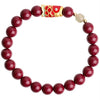 Red cinnabar beaded bracelet with a gold and red koi fish charm on a wooden plate