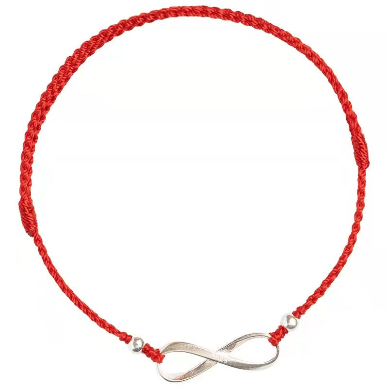 Close up of a red braided cord bracelet with a silver infinity symbol centerpiece