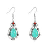 A pair of silver-tone teardrop earrings with a turquoise-colored stone and red accent bead
