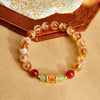 Close up of a citrine and red agate beaded bracelet with a gold tone silver charm on a wrist