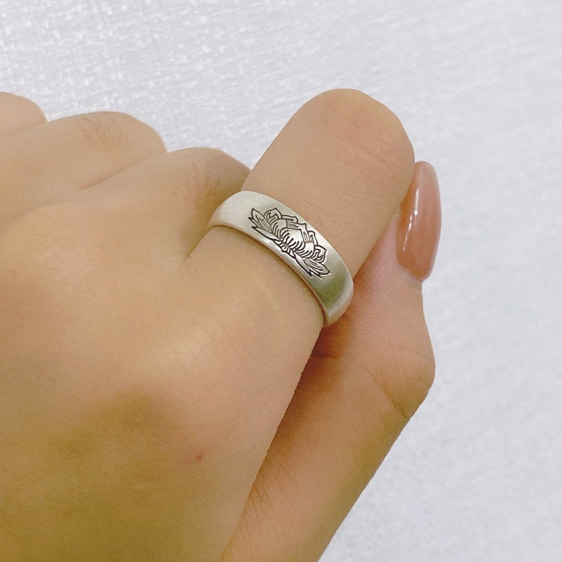 Silver-tone copper ring with lotus engraving worn on a finger