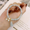 Close up of a jade beaded bracelet with pearl accents and a gourd pendant on a hand