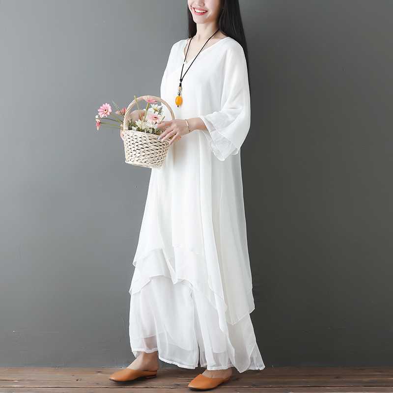Model wearing a white layered cotton tunic dress and wide leg pants holding a flower basket