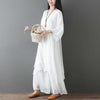 Model wearing a white layered cotton tunic dress and wide leg pants holding a flower basket