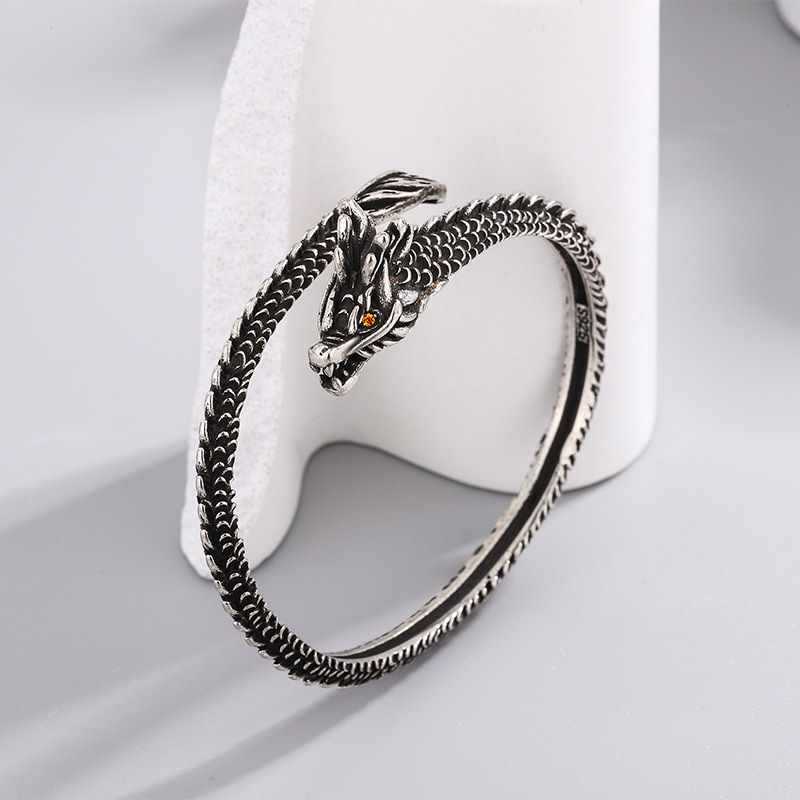 Close-up view of a silver-tone copper dragon bangle with scale texture on a white display stand