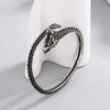 Close-up view of a silver-tone copper dragon bangle with scale texture on a white display stand