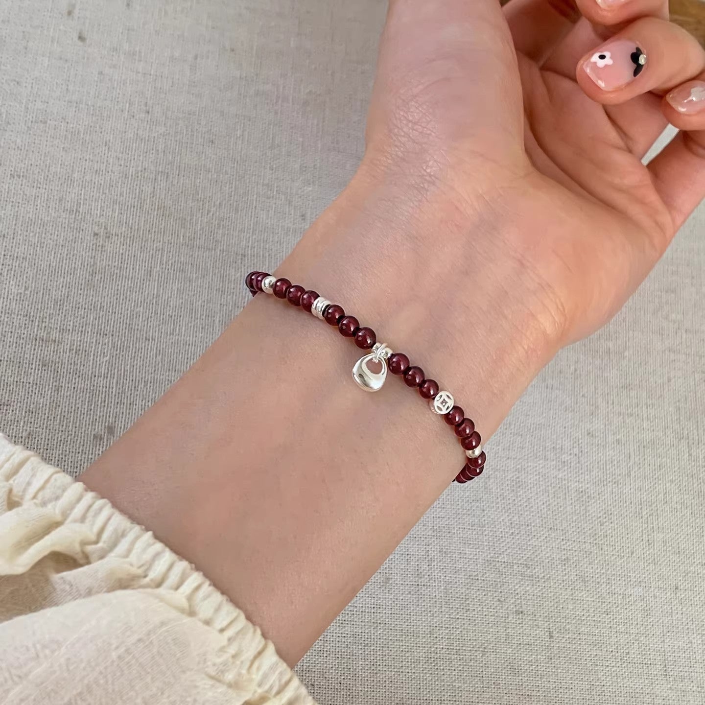 Close-up of a garnet bead bracelet with silver charms on a wrist