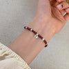 Close-up of a garnet bead bracelet with silver charms on a wrist