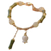 Close up of an olive jade bamboo bracelet with a white lily charm on a wrist