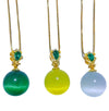 Three cat's eye round ball pendants in green, yellow, and white on gold chains