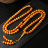 Coiled natural amber round bead mala necklace with yellow tassel on dark slate background