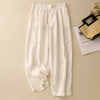 White cotton linen harem pants with frog buttons laid flat