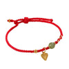 Close up of a red woven bracelet with a green jade bead and a gold tone heart charm.