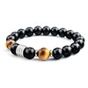 Close-up of a wrist wearing a black and gold Tiger Eye beaded bracelet with a silver tone spacer
