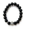 Close up of a black obsidian beaded bracelet with a silver charm on a wrist