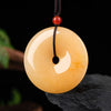 Round golden silk jade peace buckle pendant hanging from a dark cord
