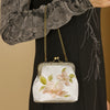 White embroidered handbag with pink flowers and green leaves held by a model