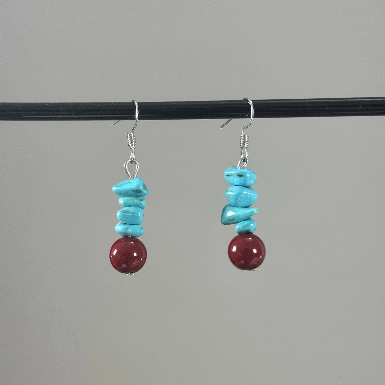 Pair of dangle earrings with blue turquoise chips and a red round bead on silver hooks