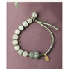 Close-up of a green jade Pixiu bracelet with a gold charm on a wrist