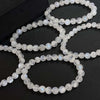 Several strands of polished cream moonstone bracelets on a dark surface