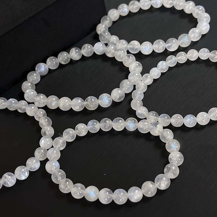 Several strands of polished cream moonstone bracelets on a dark surface