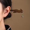 Close up of a wooden cat shaped hair pin in dark brown wood worn in black hair