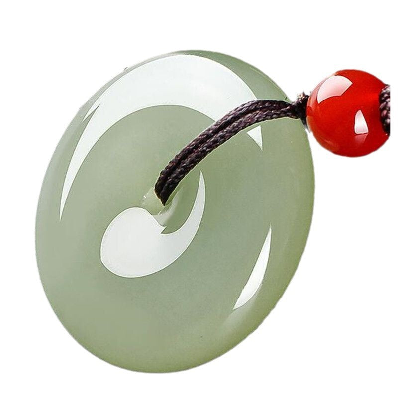 Close-up of a light green polished glass peace buckle pendant on a dark cord
