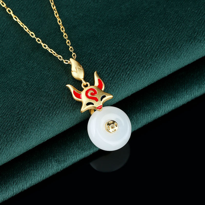 Gold tone necklace with a red and gold fox charm hanging over a white round pendant.