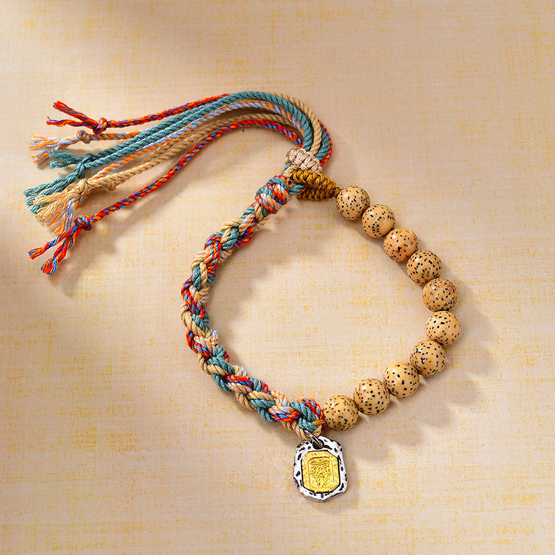 A multi-colored braided rope bracelet with bodhi seed beads and a gold-tone charm.