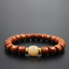 Close-up of a wooden bead bracelet with a cream-colored bone center bead and gold-tone spacers on a dark background