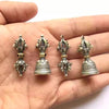 Four small copper pendants in hand showing vajra and bell designs