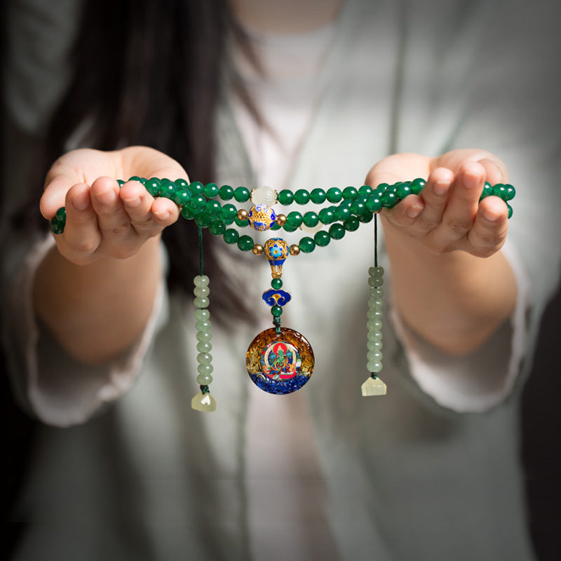 Hands holding a green agate 108 bead mala necklace with a colorful round pendant