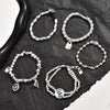 Collection of silver-plated beaded bracelets with geometric and heart charms on dark stone background