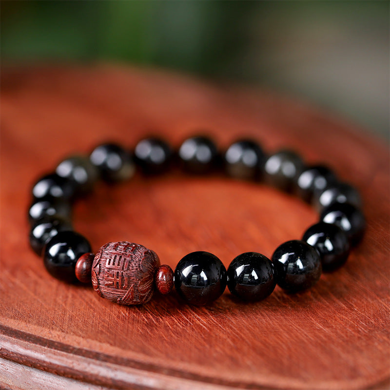 Close up view of black rainbow obsidian beads with a carved brown center bead