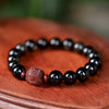 Close up view of black rainbow obsidian beads with a carved brown center bead