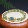 Light green jade beaded bracelet with gold-tone metal accents and a carved center charm