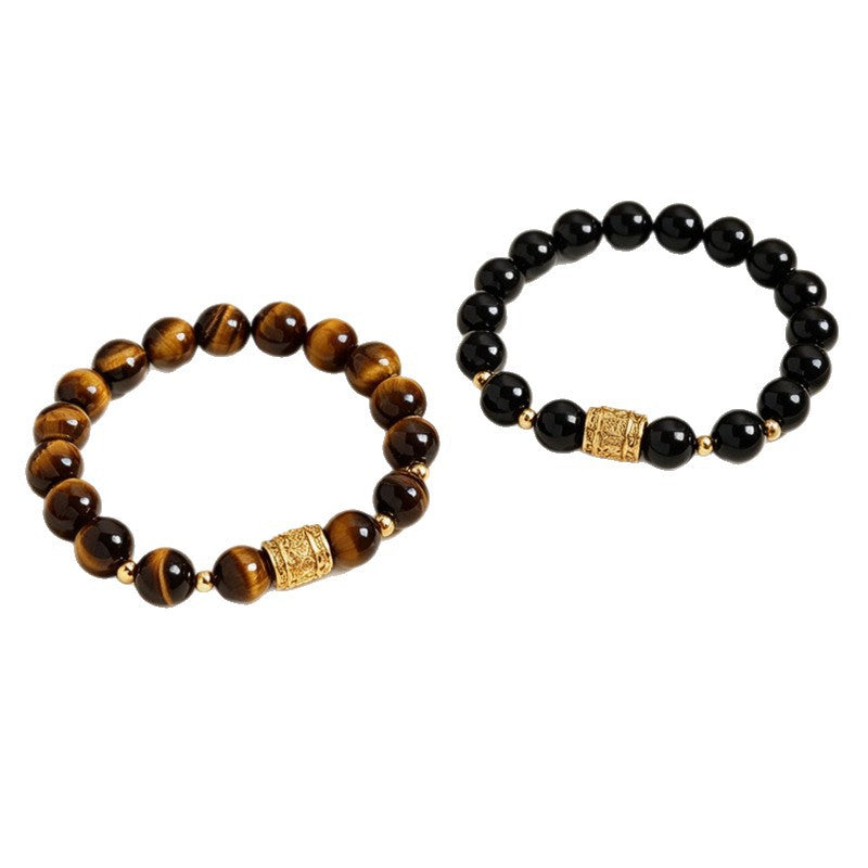 Close up of a yellow tiger eye bead bracelet with a gold tone center charm on a white tray.
