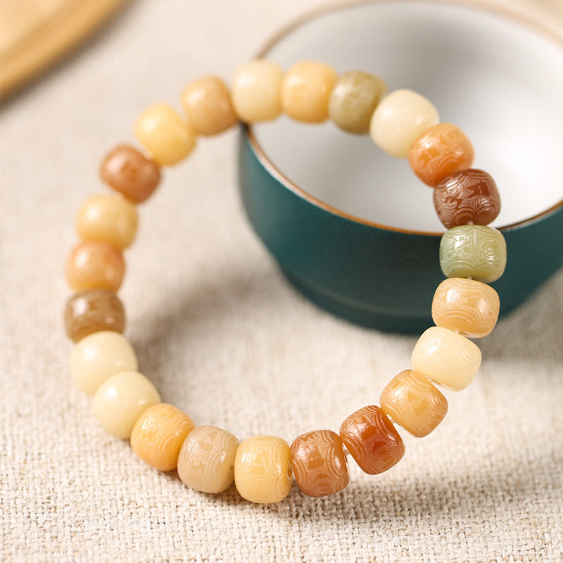 Close up of a multi-colored bodhi seed bead bracelet with carved text