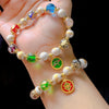 Hand holding a bracelet with colorful glass beads and a green deity charm