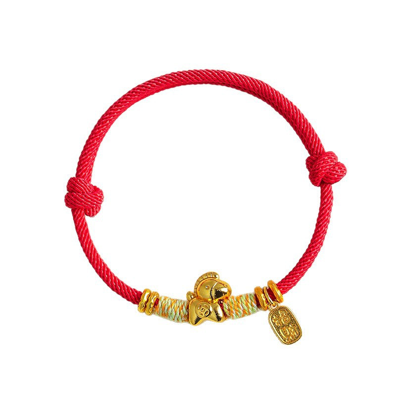 Close up of a red braided bracelet with a small gold horse charm and coin pendant