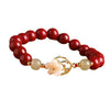 Close up of a red cinnabar beaded bracelet with a white shell flower charm