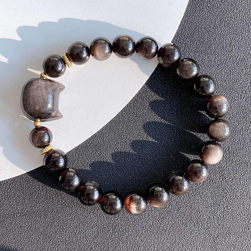 Close up of a black obsidian bracelet with a silver sheen cat head charm